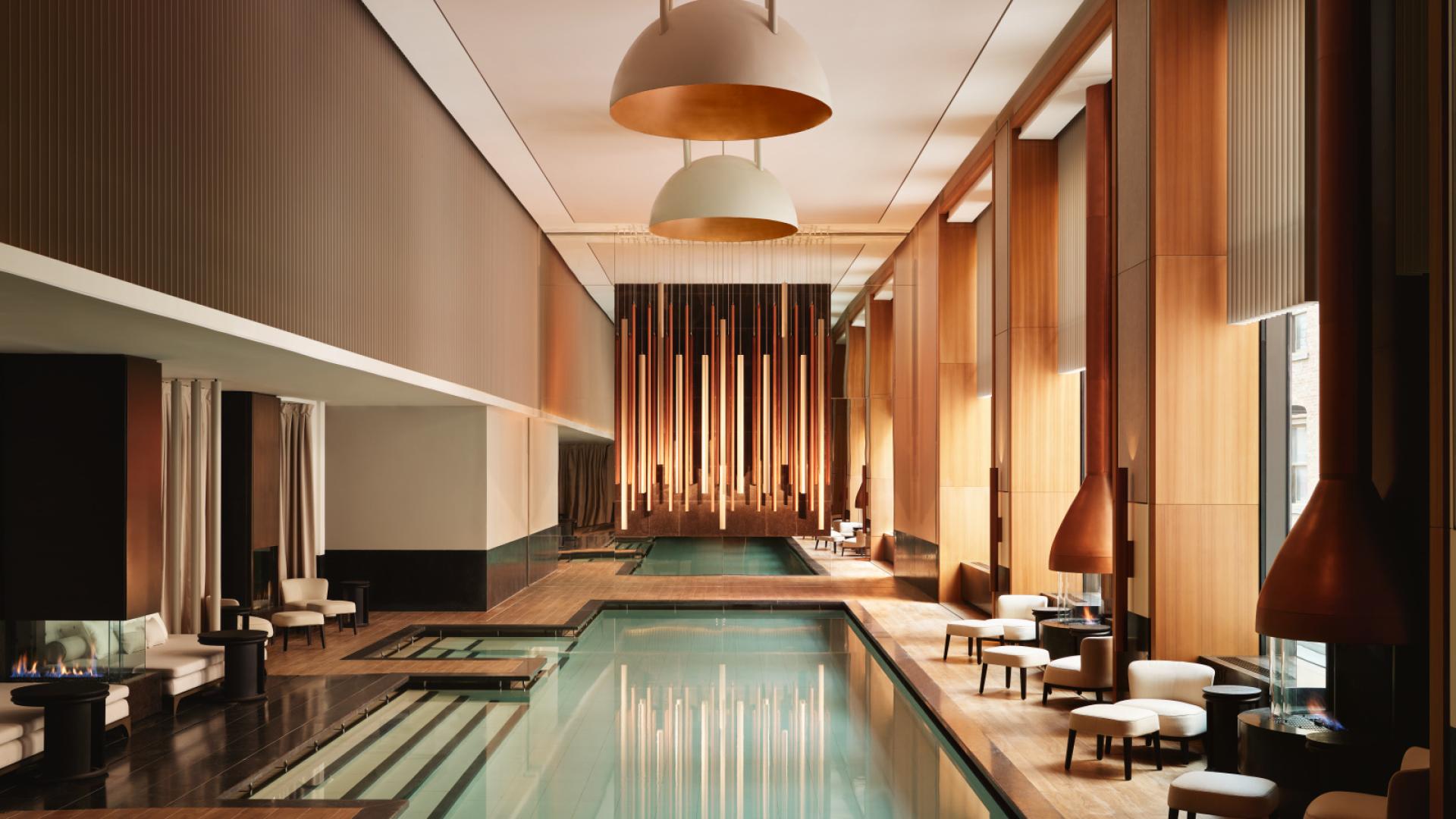 Luxurious indoor pool with wood accents and elegant lounge seating.