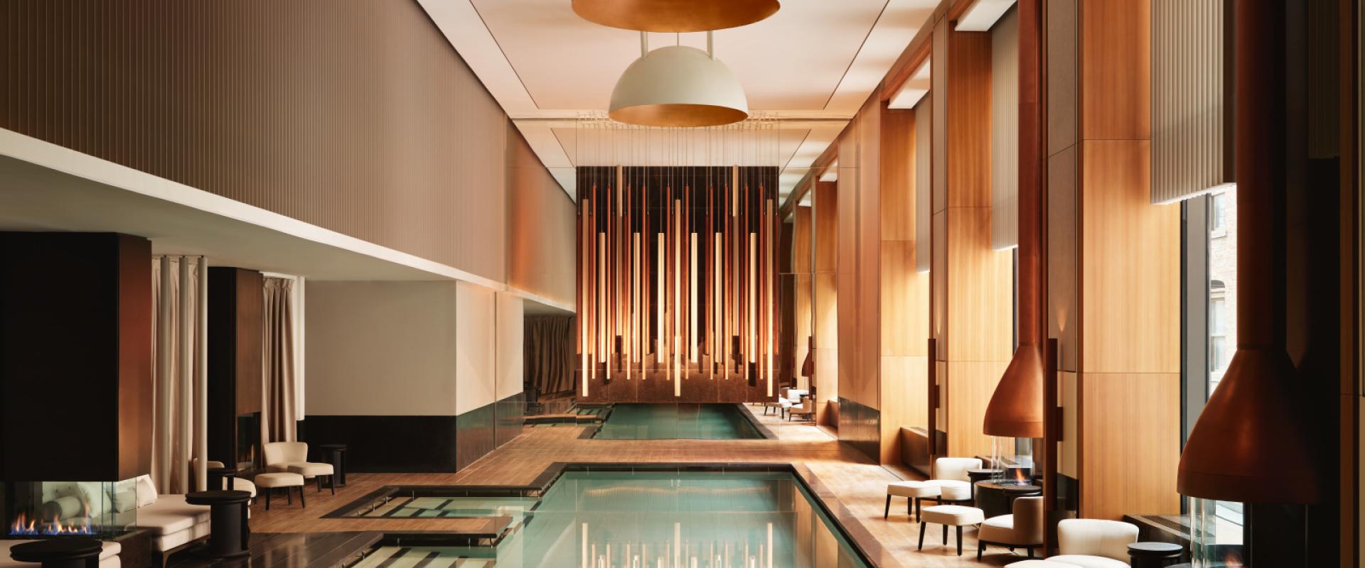 Luxurious indoor pool with wood accents and elegant lounge seating.