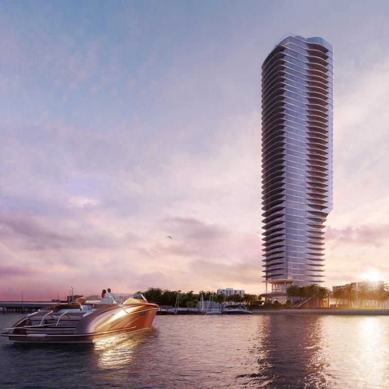 A modern high-rise tower by the water at sunset with a luxury boat in the foreground.